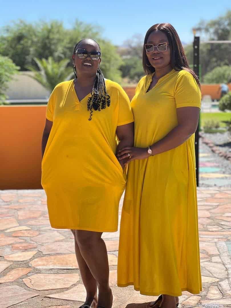 Two guests in yellow dresses by the orange wall