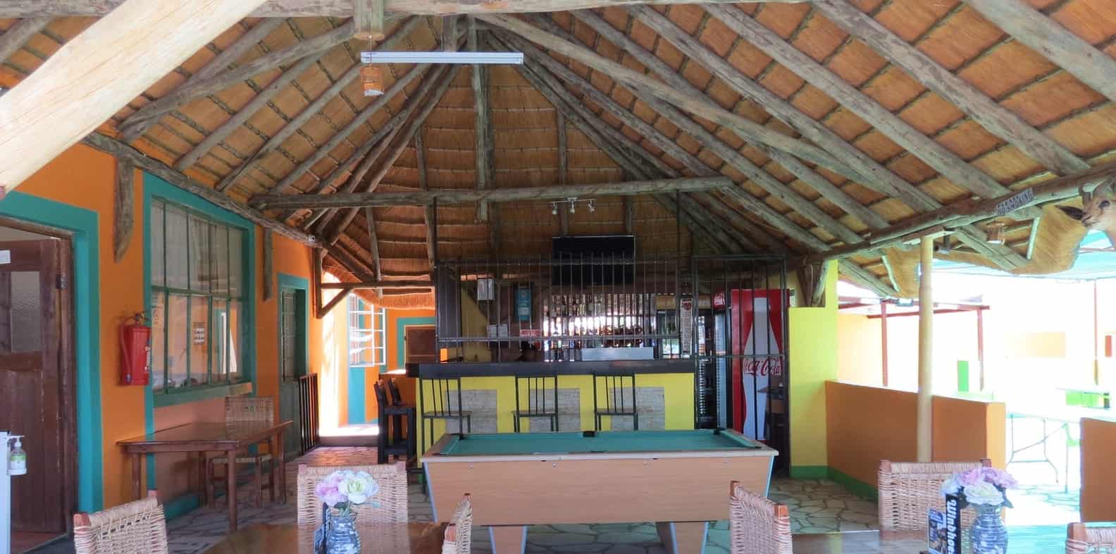 Thatched hall with pool table and wicker chairs