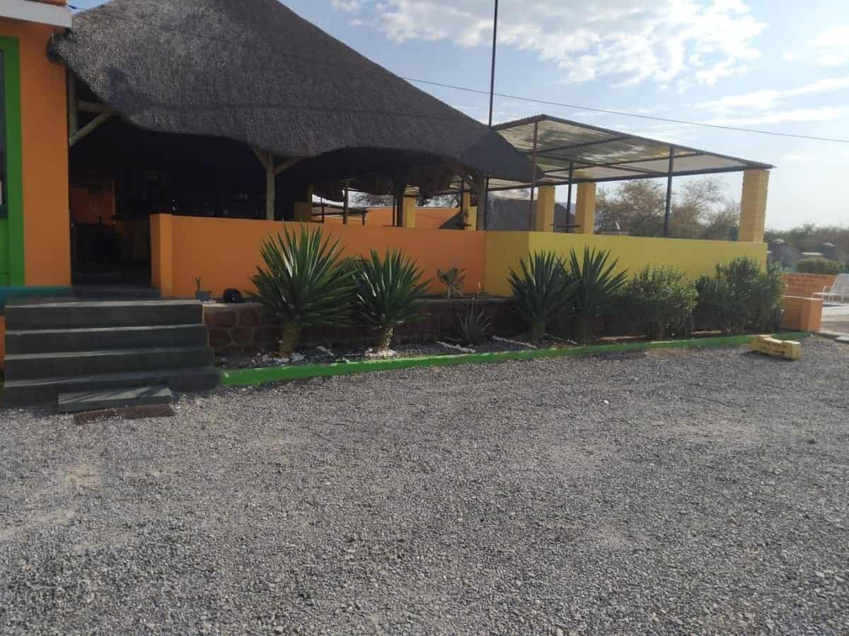 Thatched lapa over gravel parking in the morning light