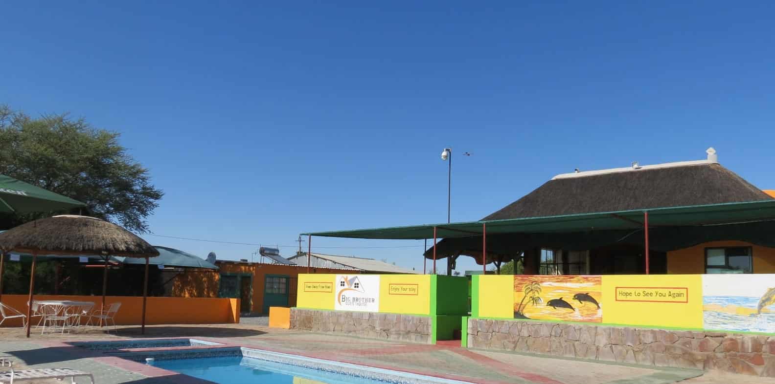 Pool under shade sails beside the yellow wall