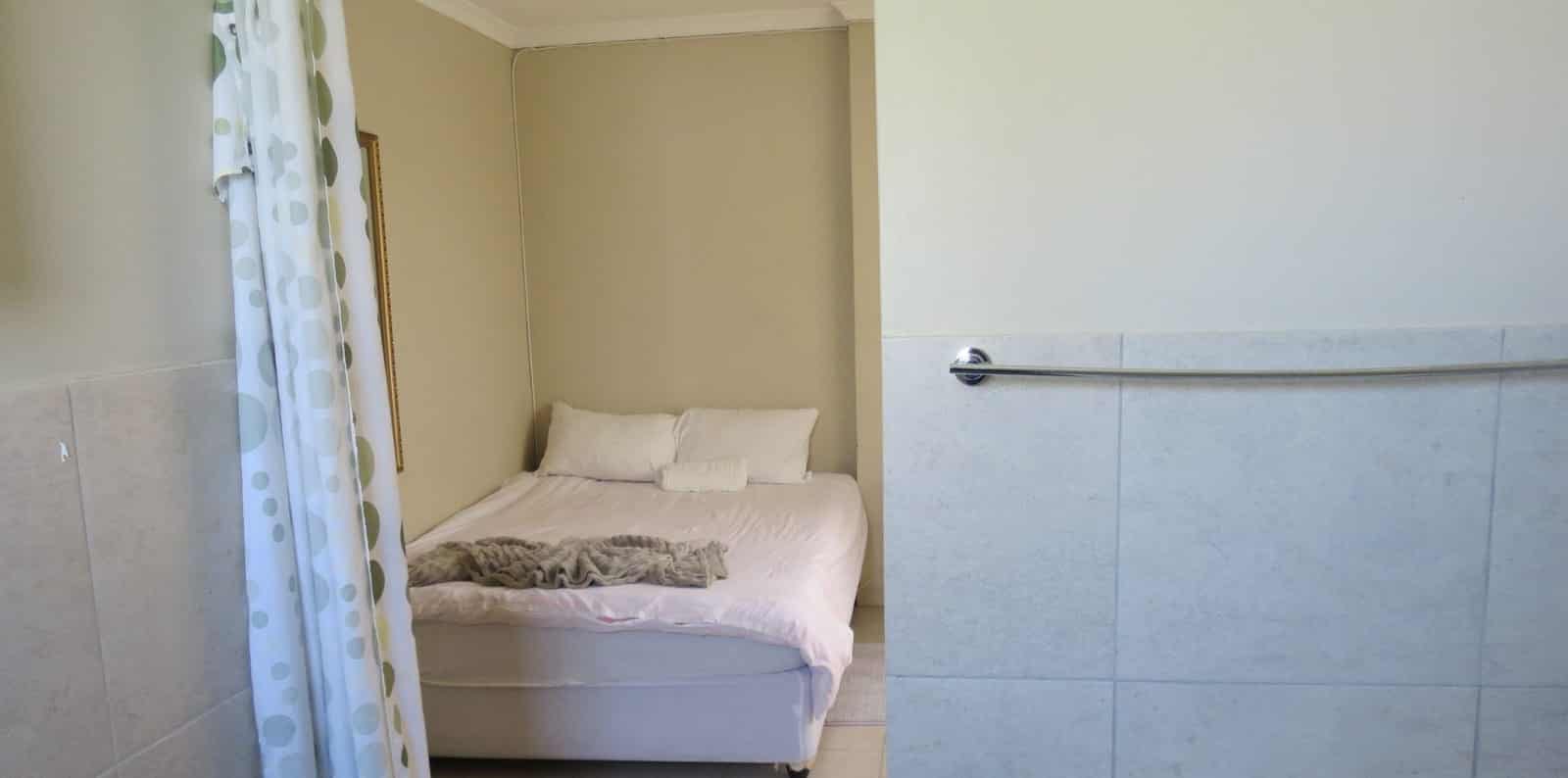 Bed beside the towel rail and shower curtain