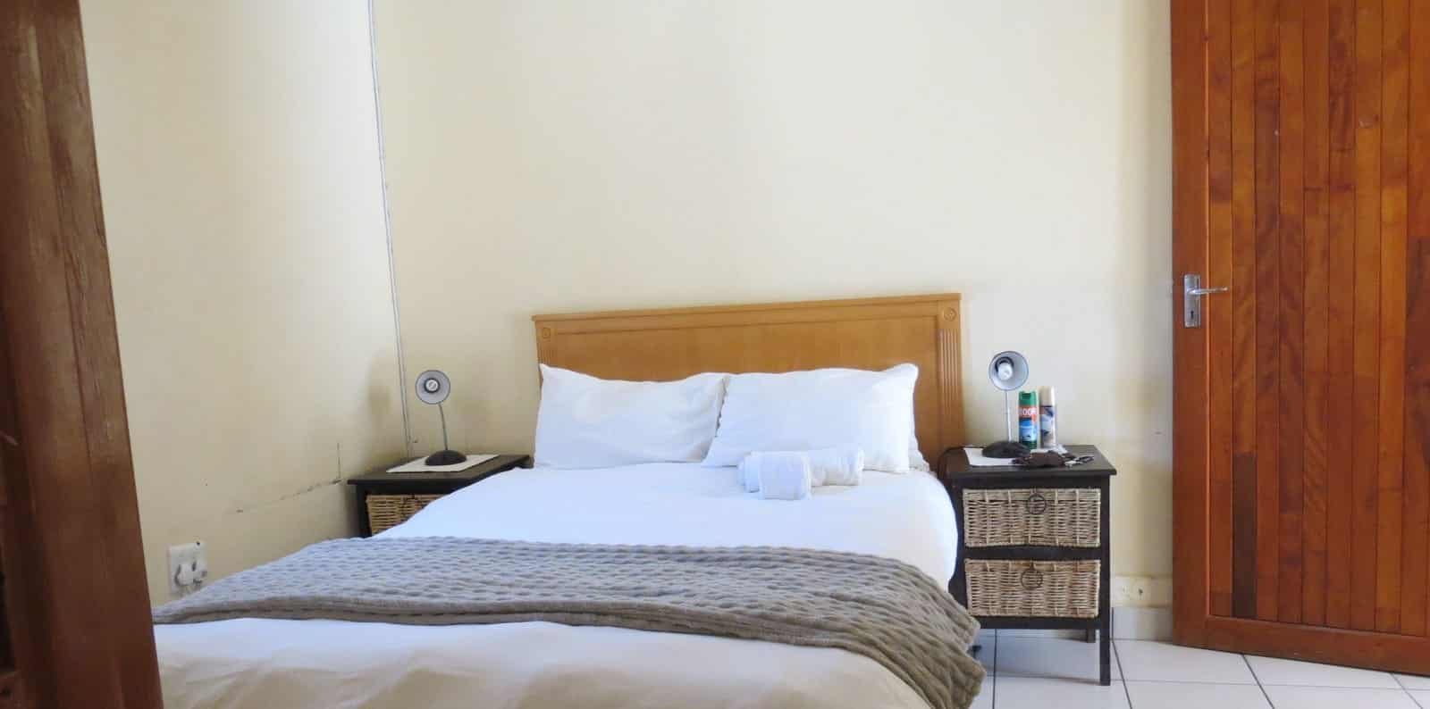 Double bed with grey throw and bedside lamp