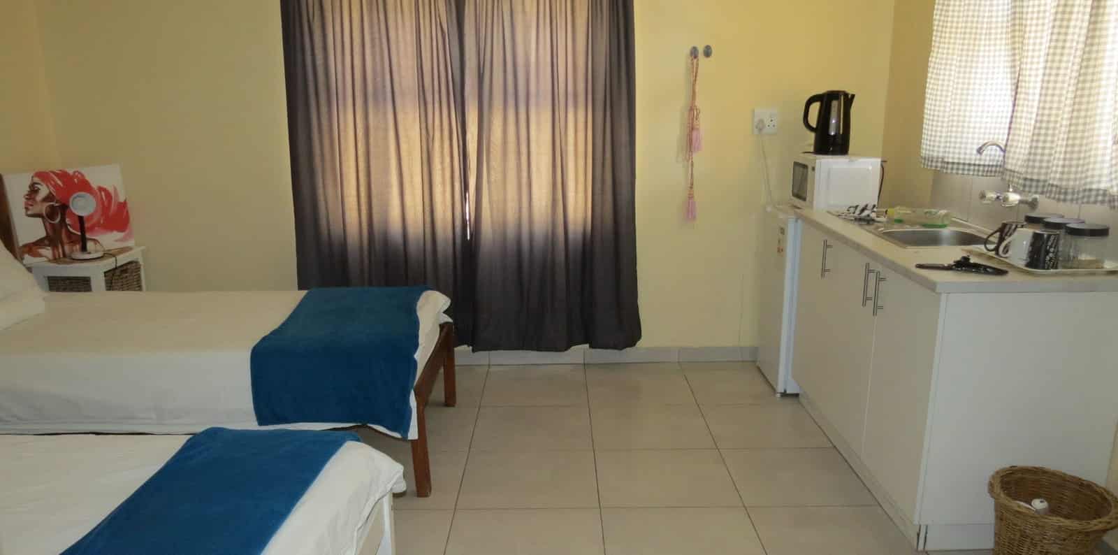 Room with kitchenette counter beside the beds