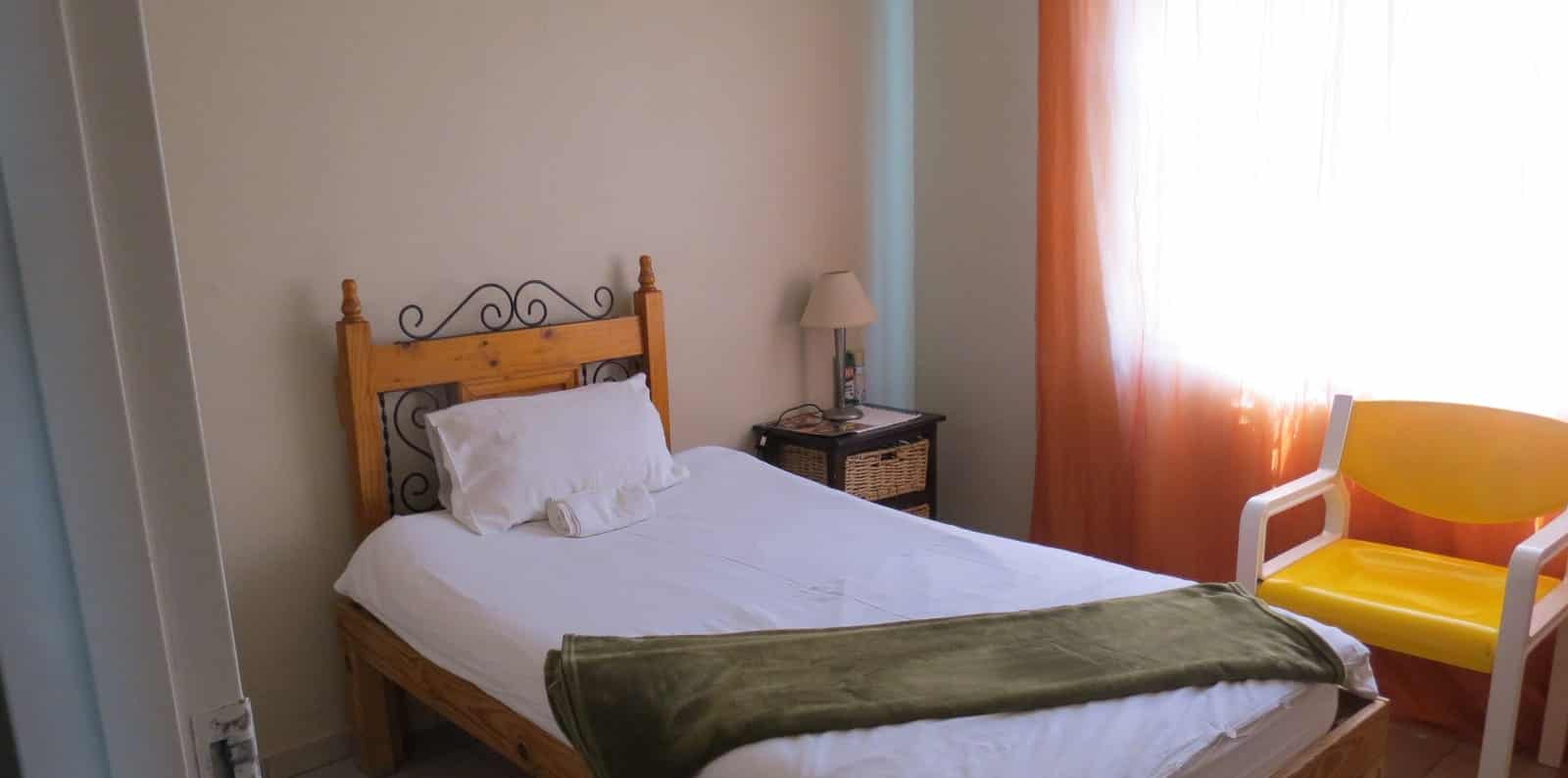 Single bed with a wooden frame and orange chair