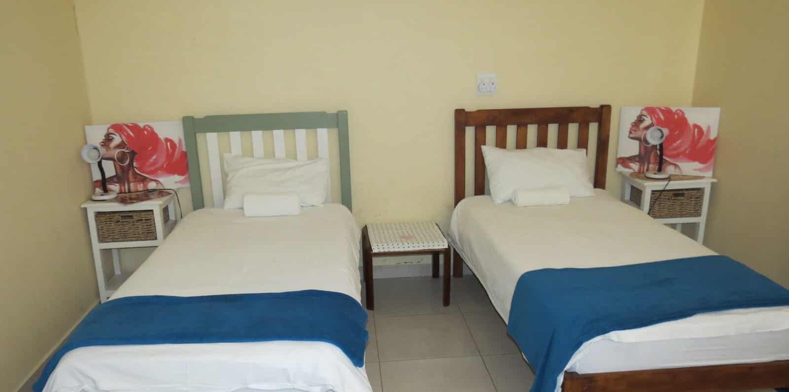 Twin beds with blue runners and floral art