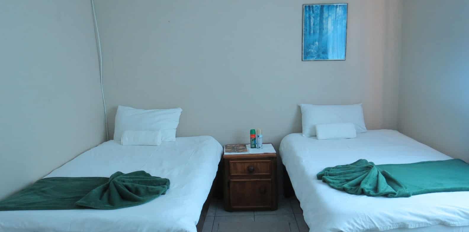 Twin beds with green throws and blue wall art