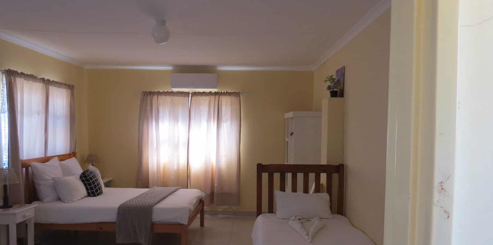 Twin beds by a bright window with an orange runner