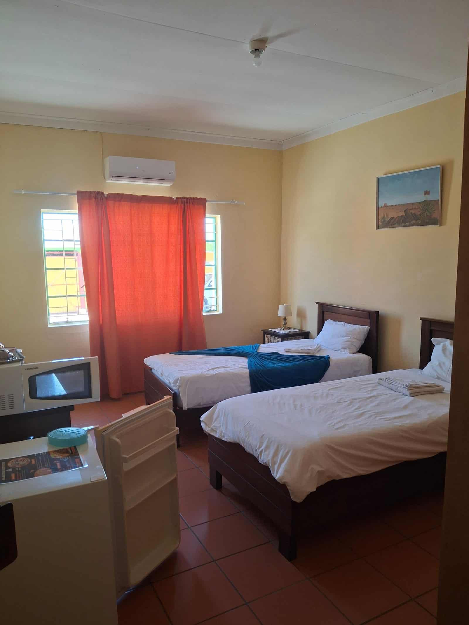 Twin beds with a television, wall art and warm curtains